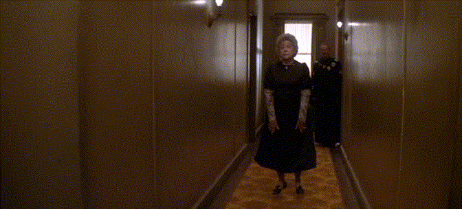 An old lady floats down a hallway.